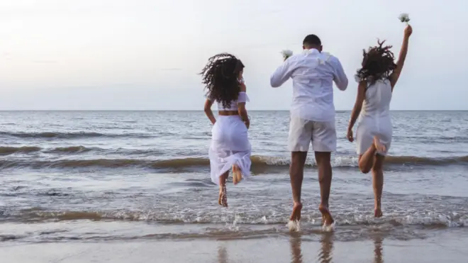 Pessoas pulando onda na praia vestidosganhar dinheiro realbranco