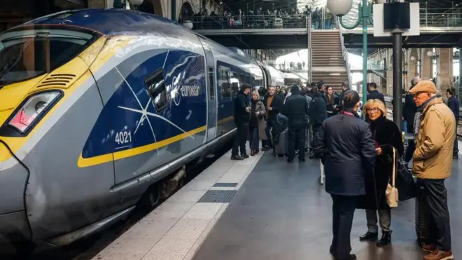 銀色に青と黄で塗られたユーロスターの列車が駅構内に止まり、プラットホームには当惑した表情の乗客が大勢立っている。ホームの上をまたがる橋にも乗客が大勢立っている