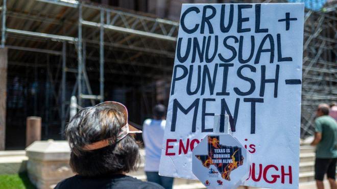 Pessoas segurando cartaz que falajogo bacará'crueldade'