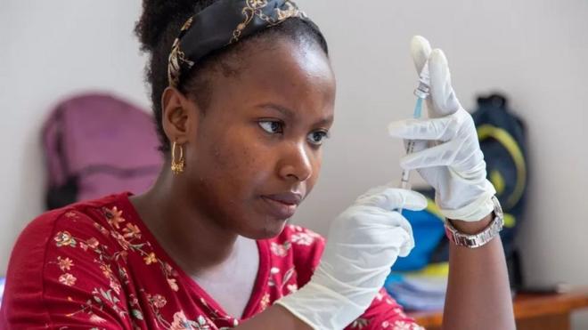 Uma mulher se preparando para dar uma vacina contra a malária