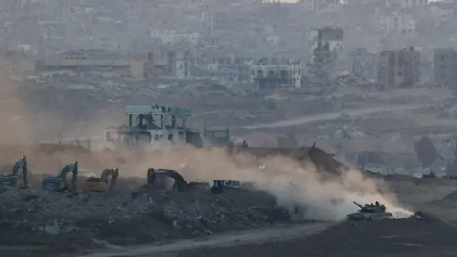 Israeli tank manoeuvres near heavy machinery, with a view of destruction in North Gaza, in the background, as seen from the Israeli side of the border, July 17, 2025. 