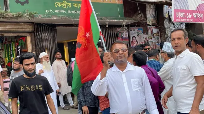 বিএনপি পার্টি অফিসের সামনে দলের পতাকা হাতে একজন কর্মী