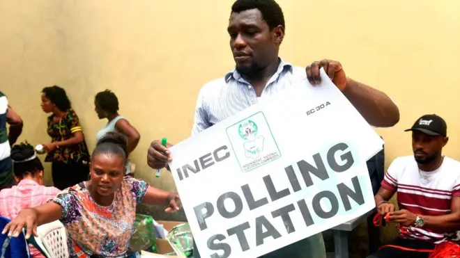 One worker hold election poster dem go display for one polling station for Nigeria 