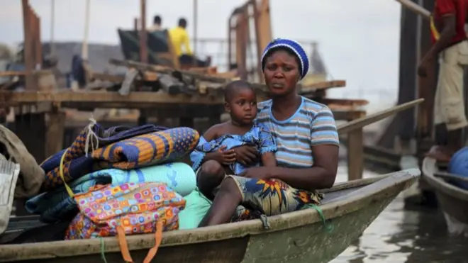 A woman sits in a canoe with her belongings as the metropolitan government begins the demolition of structures in the Makoko riverine community in Lagos July 16, 2012.