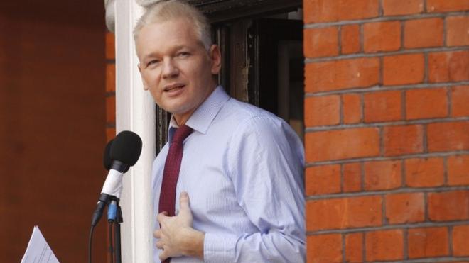 Julian Assange reads a statement to the media from the window of the Ecuadorean embassy
