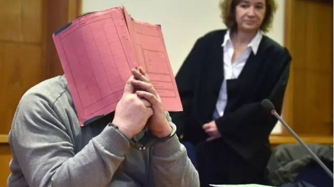 Niels H hid behind a folder as he awaited sentence in court in Oldenburg