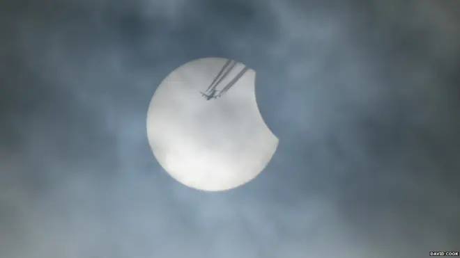 Clear viewing opportunities were restricted by the cloud cover that shrouded much of the country but David Cook from Blackburn, England, managed to capture the moment a plane passed across the sun during the initial stages of the eclipse.