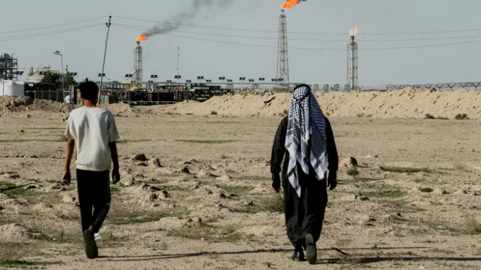 عراقيان يسيران بالقرب من الأراضي الزراعية المجاورة لحقل الزبير النفطي قرب البصرة