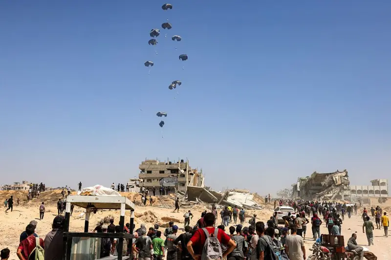 Palestinians watch a military plane delivering humanitarian aid from the United Arab Emirates and Jordan to northern Gaza on July 27, 2025.