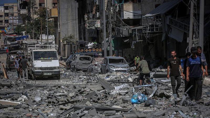 በፍንዳታ የተጎዳ ሕንጻ እና መኪኖች የሚታዩበት በፍርስራሽ የተሸፈነው የጋዛ ከተማ ሪማል አካባቢ መንገድ