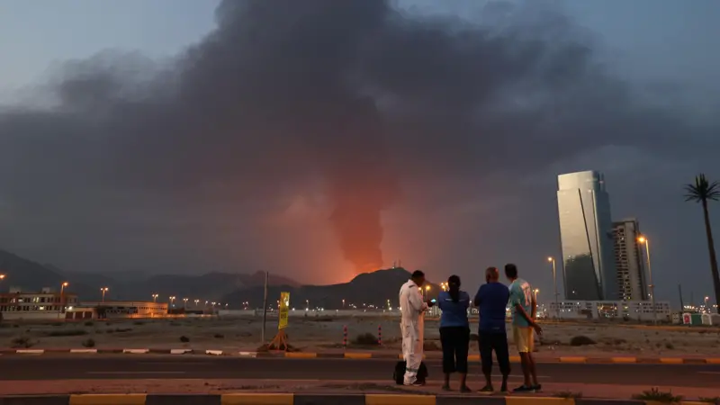 ينظر عمال إلى سحابة من الدخان الأسود عقب انفجار في المنطقة الصناعية بإمارة الفجيرة في دولة الإمارات العربية المتحدة، في 3 مارس/آذار 2026.