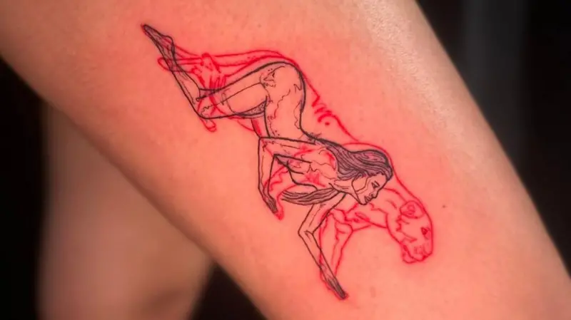 A thigh tattoo shows a woman's face merging with lioness features, representing strength.
