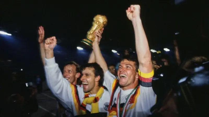 لاعبان من منتخب ألمانيا الغربية الفائزة بكأس العالم 1990 يحملان الكأس