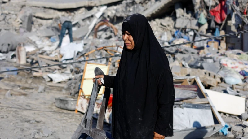 امرأة فلسطينية تحمل كرسياً في موقع غارة إسرائيلية على منزل في دير البلح، 19 يوليو/تموز 2026.