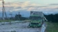 地震で道路の舗装がはがれガードレールが曲がっている。停めてあるトラックも荷台が大きく損傷している