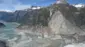 Dağlar arasındaki dar bir geçitten buzlu bir deniz uzanıyor. Dağların dik yamaçlarının büyük bölümü yeşil bitki örtüsünden arınmış; bunun yerine gri, parçalanmış kayalıklar ortaya çıkmış durumda. Dağların zirveleri karla kaplı ve aşağıdaki fiyortta buzlar parıldıyor.