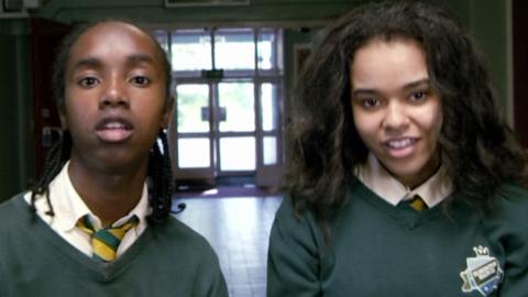 Two schoolchildren in a corridor.