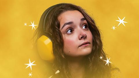 A young girl with long brown hair and wide eyes is staring into the distance. She is wearing bright yellow ear defenders and is surrounded by stars and yellow/orange clouds