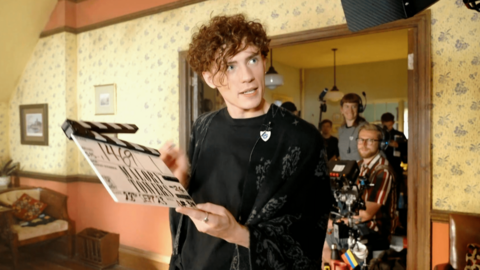 Joel is holding a clapperboard on the set of Malory Towers