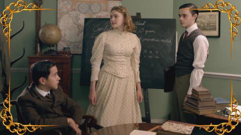 Two boys and a girl, standing and sitting in a school room, forming a plan, set in a gold frame.