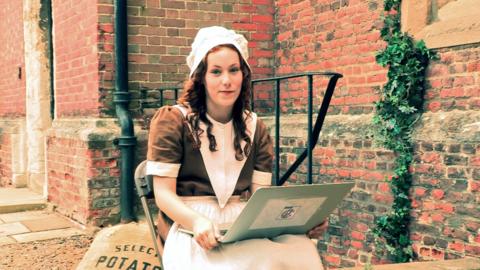 Isabel Clifton aka Hetty Feather in victorian clothes with a laptop.