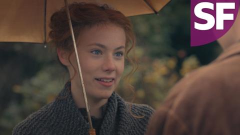 A smiling Hetty Feather holds an umbrella.