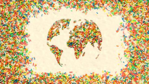 Multi coloured cake sprinkles in the shape of the globe on a butter cream background