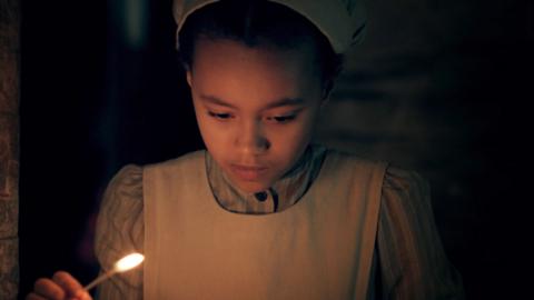 Lizzie lights a candle in the cellar.