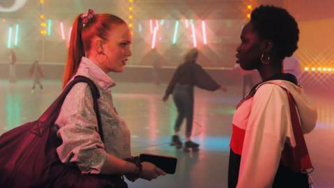 Two girls prepare to go to a roller disco together.