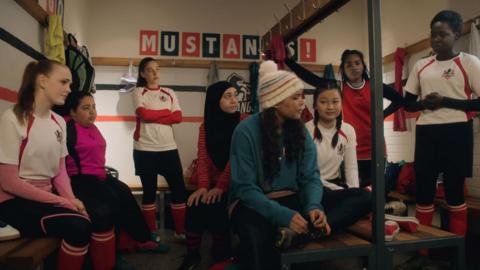 The Mustangs FC team gather in a lockroom to comfort TJ.