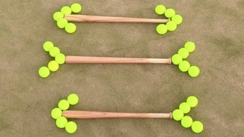 Three bats on grass. Each bat has tennis balls lined up at opposite ends off the handle and tip of the bat.