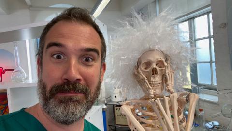 Doctor Chris poses with a spooky skeleton.