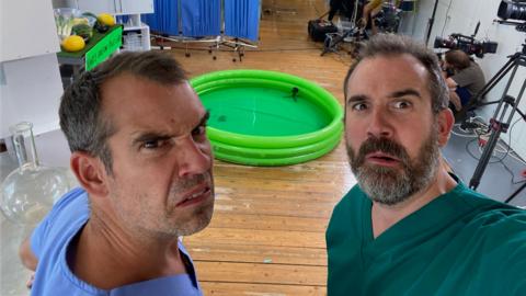 Doctors Chris and Xand look concerned in front of a small paddling pool.