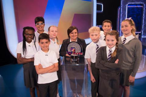 The finalists stood with the presenter who is holding the trophy.