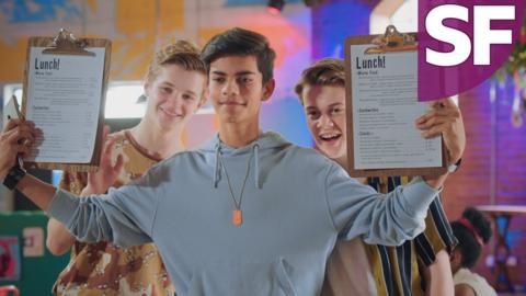 Three boys in a cafe, Nate, Harry and Oakley. They are holding up cafe menus and smiling.