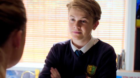 Close up of Harry face, smiling. He is wearing a school uniform.