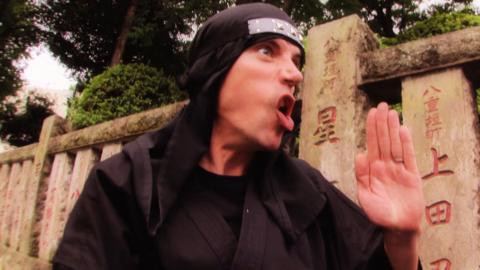 A man dressed as a ninja pulling a funny face.