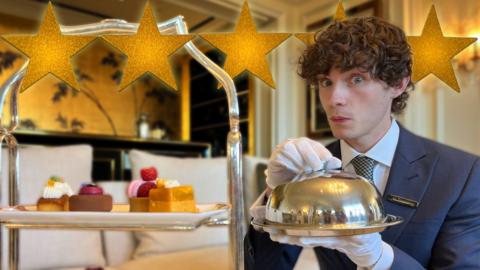 Joel holds a silver tray whilst dressed in a butler's suit.
