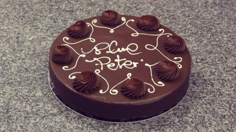 Chocolate cake with Blue Peter written on it in icing.