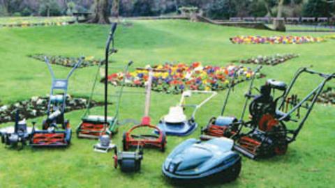 A collection of vintage lawnmowers in a garden.