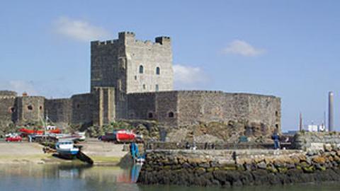 Carrickfergus Castle surrounded by boats in water.