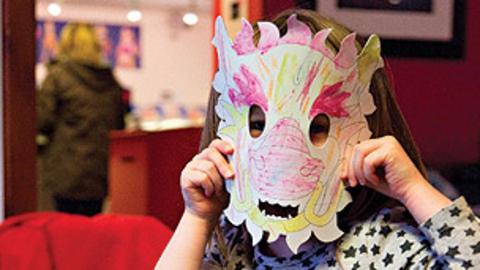 A child wearing a mask coloured in with crayons.