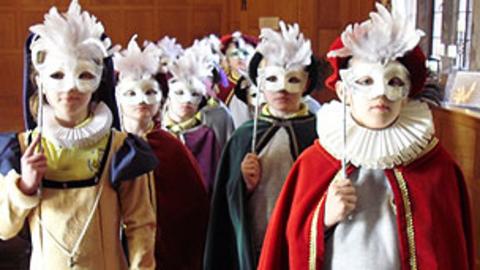 A group of children dressed in historical costume with masks on their faces
