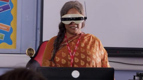 A woman standing with a virtual reality head set on.