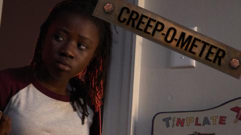 A young girl leaning through a doorway looking scared.