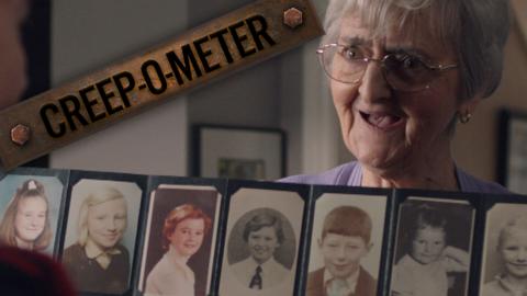 An old woman holding up a wallet filled with old pictures of children.