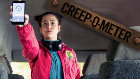 A girl inside a bus holding up a phone playing music.