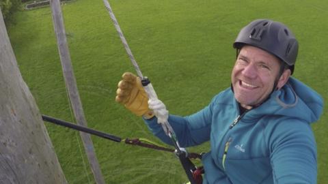 Steve Backshall climbing a pole.