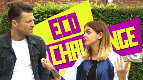 A man and woman look confused in front of a large sign saying 'Eco Challenge'.