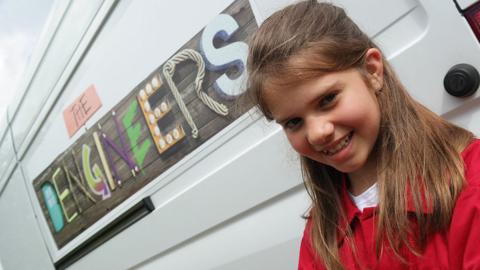 A girl stands in front of the Dengineers Den.